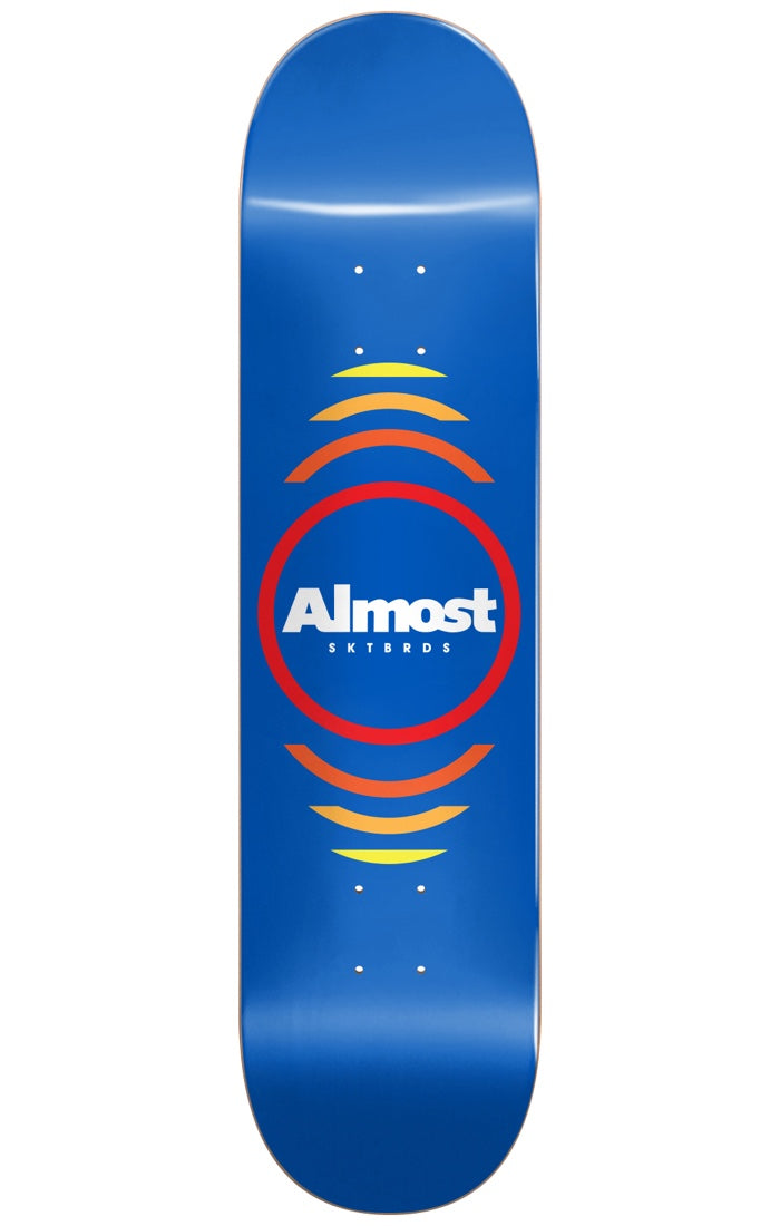 Almost Reflex BLUE 8.0 skateboard deck: A white Almost SKTBRDS logo inside a red ring, with orange-to-yellow arcs radiating above and below, on a plain blue deck.