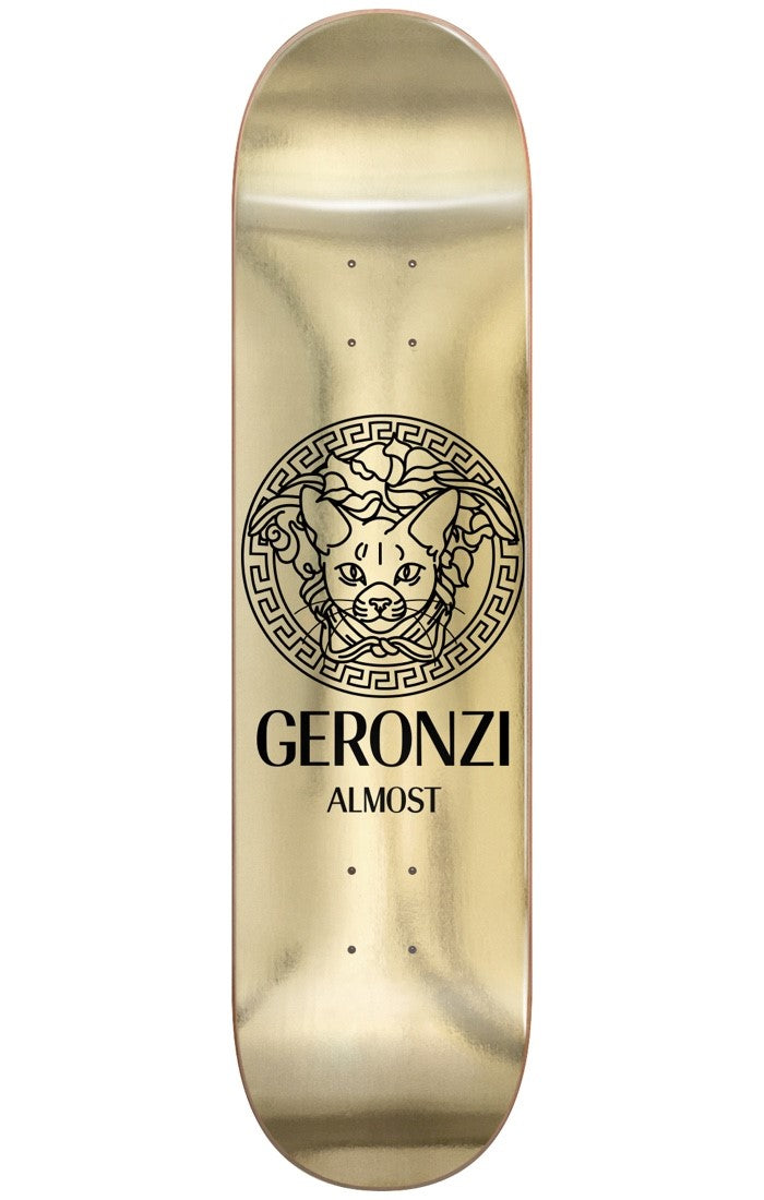 Almost Max Runway R7 8.5 skateboard deck: A black line drawing of a cat's head inside an ornate Greek-key medallion, in the style of a luxury fashion logo, on a shiny gold foil deck. 'Geronzi' and 'Almost' are printed below in black.