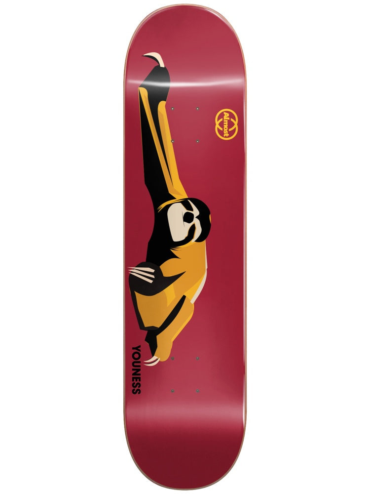 Almost Youness Animals R7 8.25 skateboard deck: Flat stylised illustration of a sloth in a yellow and black tracksuit, shades on, stretched out in a kick pose, on a plain burgundy deck. The Almost logo sits near the nose and Youness is printed at the tail.