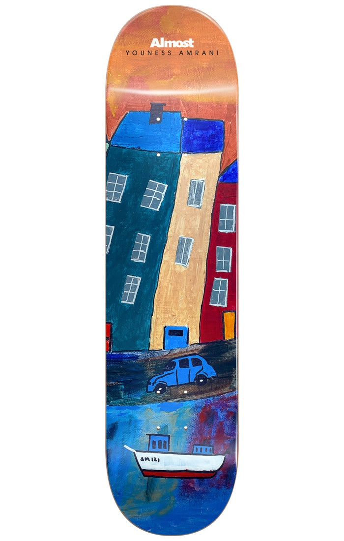 Almost Youness Places R7 LEFT 8 skateboard deck: A naive painting of leaning tall houses in teal, cream and red above a blue car and a white fishing boat on water, under an orange sky. Almost and the rider name sit at the nose.