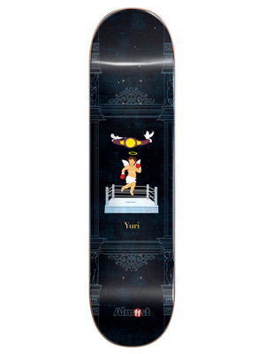 Almost Yuri Gronze Collab R7 8.3 skateboard deck: Dark navy deck with faint architectural columns and ornaments, and a small cherub with halo and red boxing gloves in a boxing ring, with a championship belt and two doves above. Yuri in gold text.