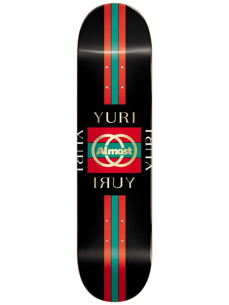 Almost Yuri Luxury Super Sap R7 8.125 skateboard deck: Black deck in a luxury-fashion pastiche: red and green vertical stripes top and bottom, and a central red and green block with a gold interlocking-rings Almost logo, framed by 'YURI' repeated in gold serif lettering.