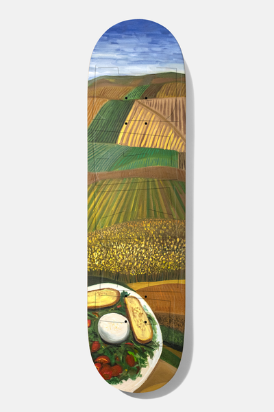 Baker Jacopo Il Pranzo Twin 8.38 skateboard deck: Painted landscape of patchwork farmland fields in green, gold and brown under a blue sky, with a plate of tomato salad, bread and mozzarella at the tail.