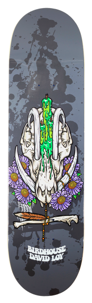 Birdhouse David Loy Shrine skateboard deck: An animal skull wearing a dripping green candle on its head, ringed with purple daisies, bones and a feather, set on a grey background with large black paint splatters.