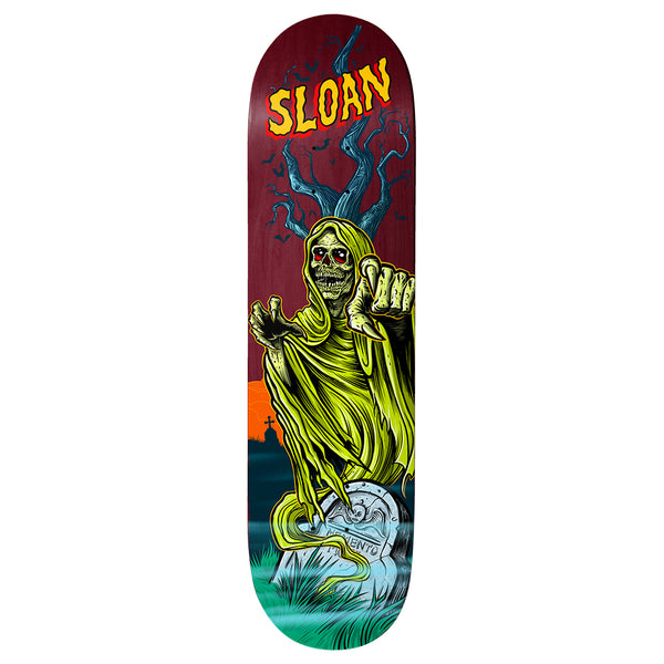 Birdhouse Elliot Sloan Graveyard 8.5 skateboard deck: A hooded green grim reaper skeleton with red eyes rises from a gravestone, pointing and reaching forward, in front of a bare tree, bats and a distant cross-topped graveyard at sunset. Yellow 'Sloan' lettering is at the nose on a maroon deck.