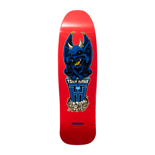 Birdhouse Hawk Gargoyle Old School 9.375 skateboard deck: A crouching blue gargoyle with horns and wings perched on a blue pedestal bearing a skull and the name, above a pile of skulls. On a red old-school shaped deck with small Birdhouse text at the tail.