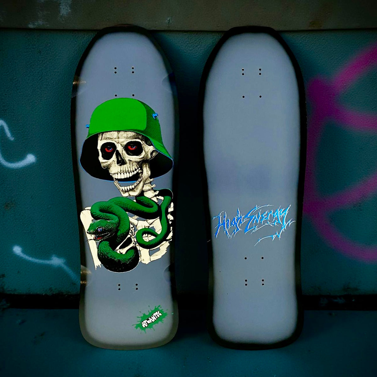 Brand-X Guardian Viper skateboard deck: Skeleton in a green army helmet with red eyes coiled by a green viper, on a pale grey old-school shaped deck with a black rim. A green splat logo sits near the tail. The second deck shows blue scratchy script.