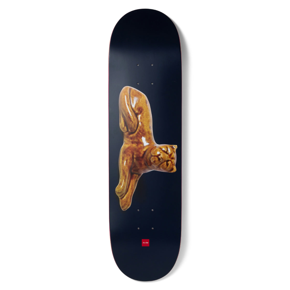 Chocolate Aikens Porcelain skateboard deck: A glossy, honey-brown glazed porcelain figure of a stretching cat, photographed against a dark navy deck. A small red Chocolate logo sits near the tail.