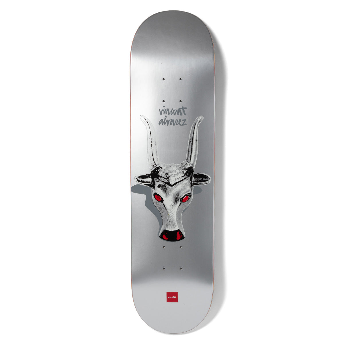 Chocolate Alvarez Longhorn skateboard deck: Metallic silver deck with a monochrome horned bull's head with glowing red eyes and nose, casting a shadow, with the rider's name in grey handwriting above and a small red Chocolate logo at the bottom.