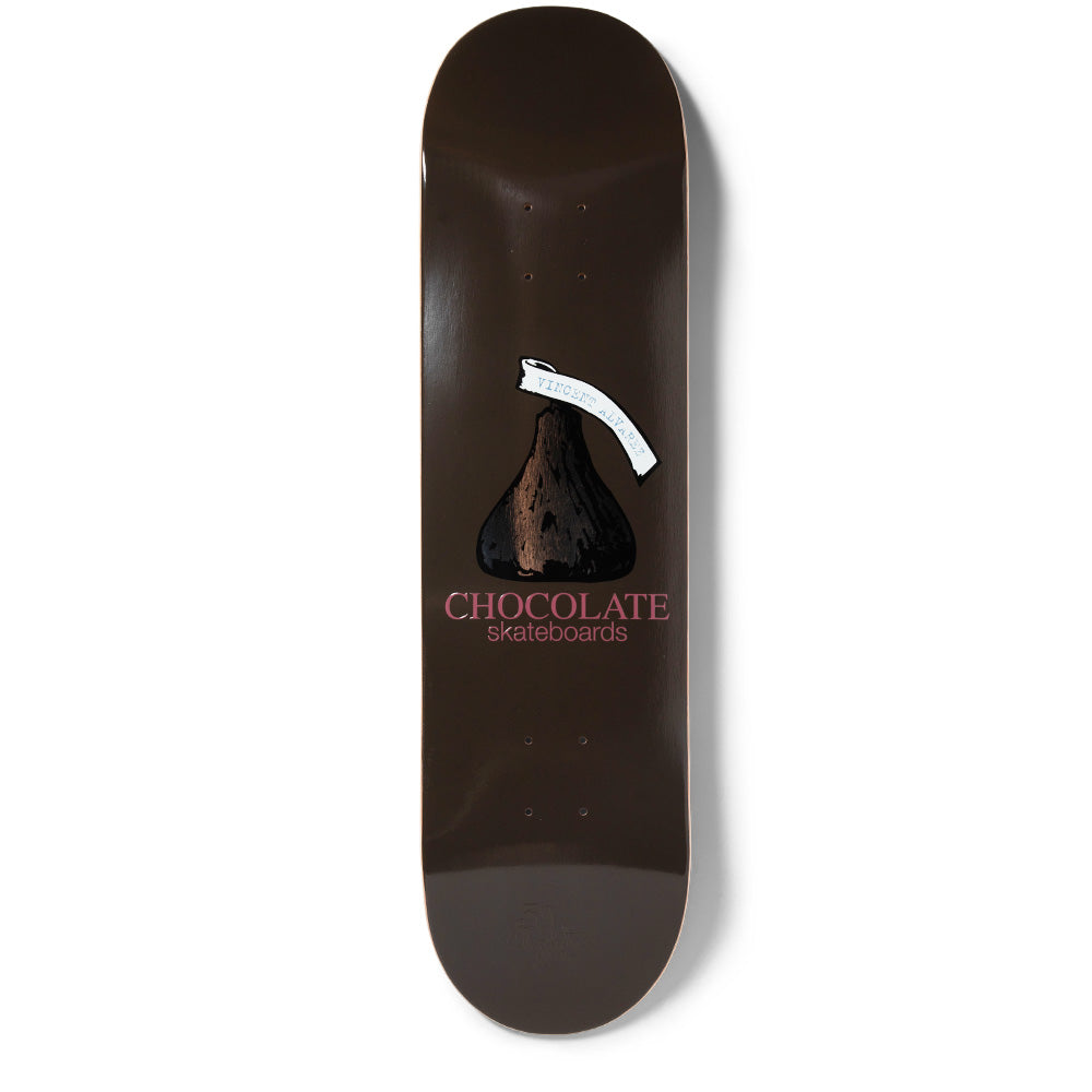 Chocolate Alvarez Kiss skateboard deck: A chocolate kiss sweet with a white paper tag on a plain dark brown deck, with 'CHOCOLATE skateboards' in pink beneath. Tag carries small typed text.