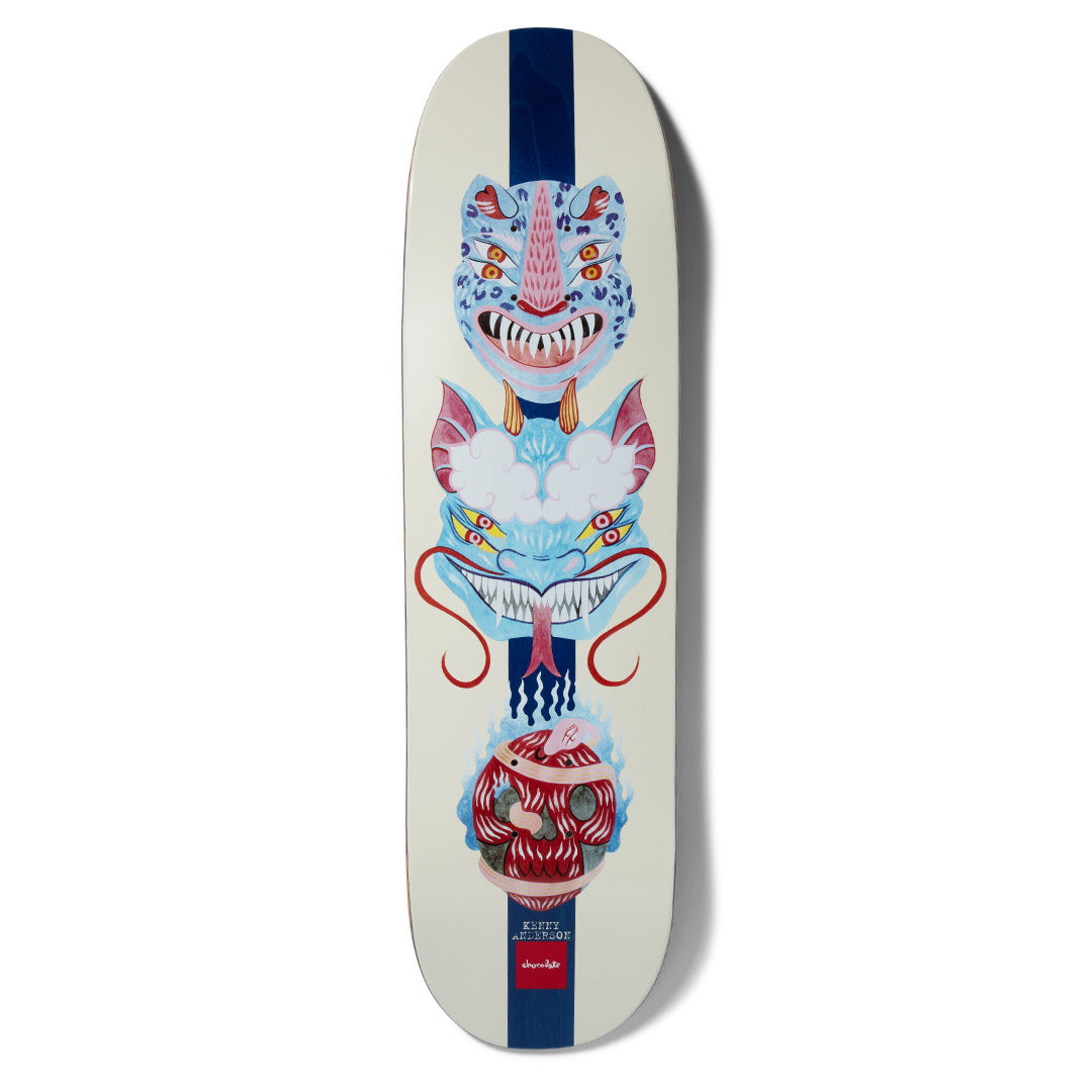 Chocolate Anderson Dog Perfume Mask skateboard deck: Three stacked painted mask-like faces, a blue leopard-spotted tiger, a blue horned dragon on clouds and a red masked head, on a cream deck with a navy central stripe. Name and Chocolate logo at the bottom.