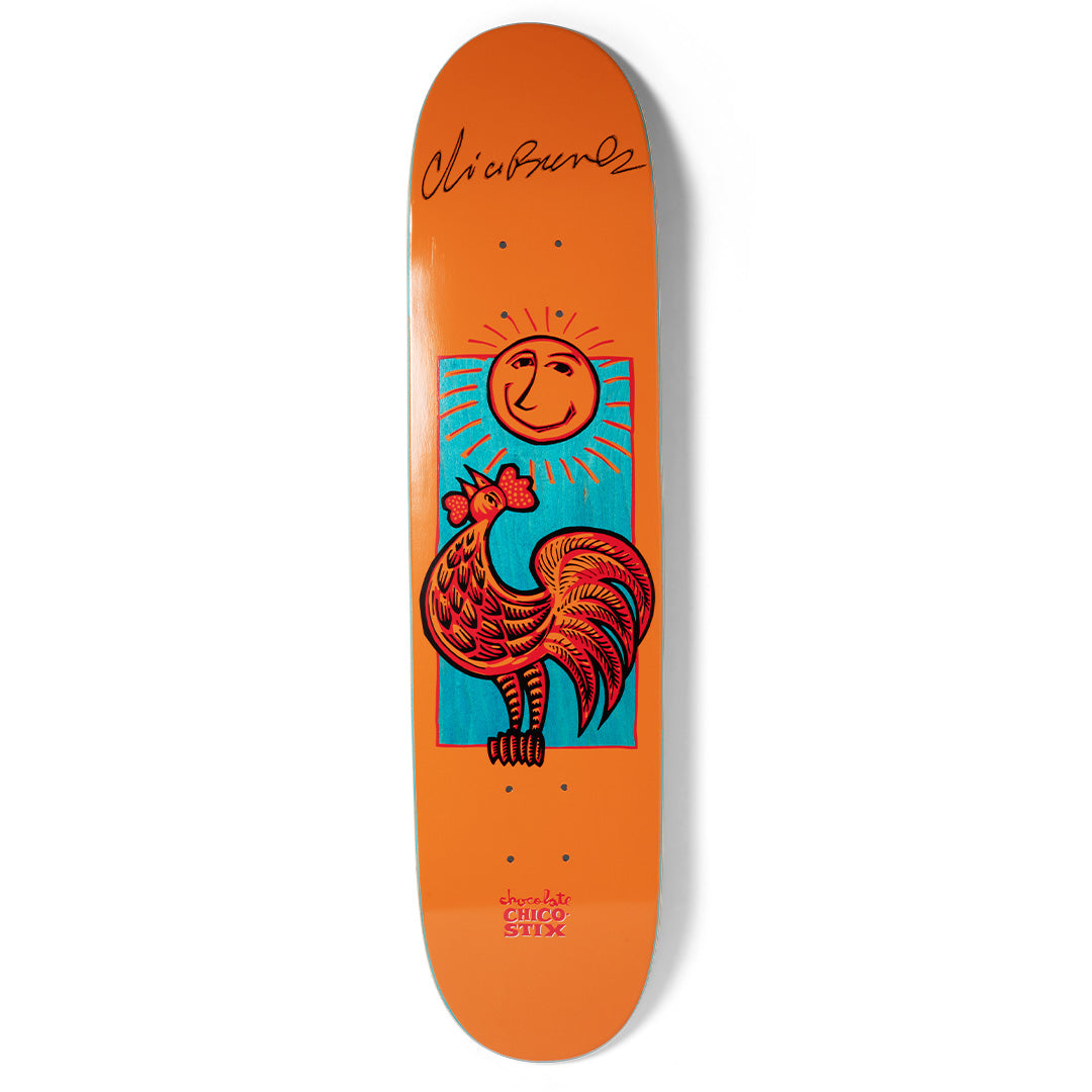Chocolate Brenes Nicaraguan Sunrise (Signed) skateboard deck: Folk-art style red rooster crowing beneath a smiling sun with rays, framed in a teal rectangle on an orange deck. A black printed signature sits at the top.