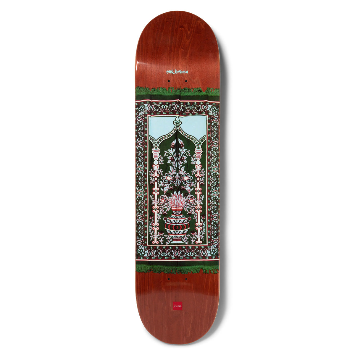 Chocolate Herrera Prayer Rug skateboard deck: Ornate prayer-rug design with a patterned border, arched window and flowering vase, in dark green, pale blue and pink with fringed edges, on a red-brown stained deck.