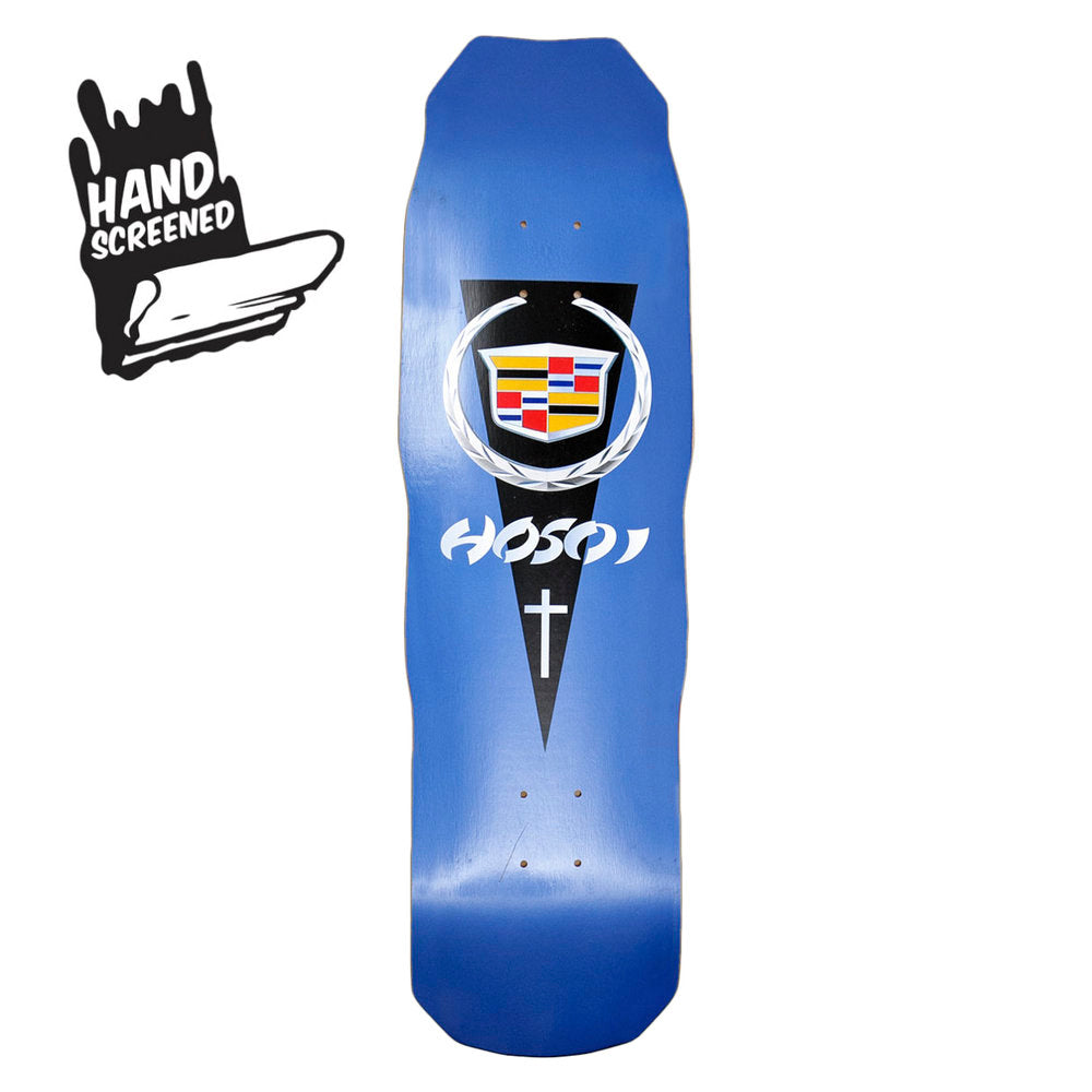 Hosoi Cadillac skateboard deck: A Cadillac-style crest in a laurel wreath on a black downward-pointing pennant, with the Hosoi name in white and a small cross below, on a blue shaped deck. A hand screened badge sits in the corner of the photo.