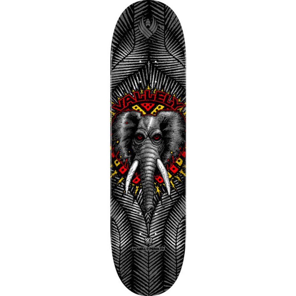 Powell Peralta Vallely Elephant Silver Foil Flight skateboard deck: A grey elephant head with tusks and red eyes sits in a burst of red and yellow tribal shapes, with the name arched above. Silver foil feather-like patterns cover the black deck.