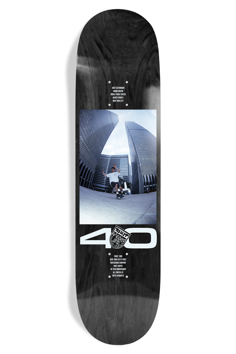 Shut Bryce Kanights Bruno EX7 skateboard deck: Fisheye photograph of a skater mid-trick between two towers of a tall twin-tower complex, in a panel on a black deck, with a large white 40 and a crest below and small credit text.