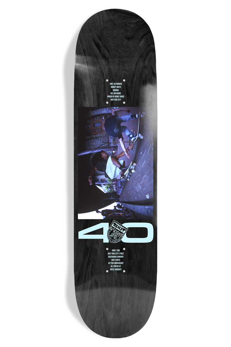 Shut Bryce Kanights Rodney EX7 skateboard deck: A dusky blue-toned photograph of skaters in a New York street, with a large pale blue 40 and a small crest below it, on a black-stained deck. Small blocks of credit text sit above and below the picture.