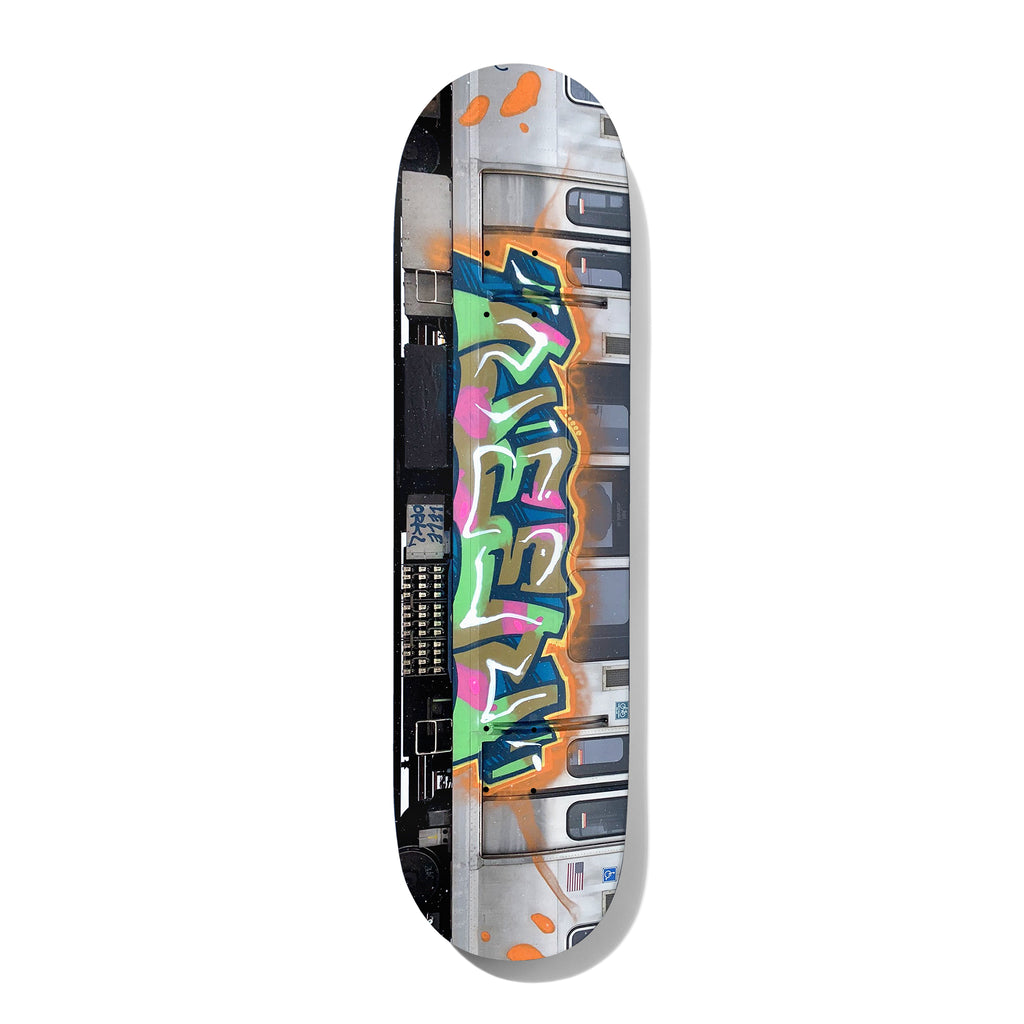 Deathwish Neen L Train 8.0 skateboard deck: Photograph of the side of a silver subway train with a large graffiti piece in green, pink, blue and gold bubble lettering outlined in orange, with windows and doors behind.
