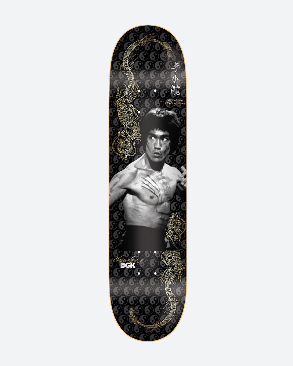 DGK x Bruce Lee Balance Embossed skateboard deck: Black and white photographic portrait of a bare-chested martial artist with claw marks across his chest, flanked by gold dragons and Chinese characters, over a repeating grey yin-yang pattern on black.