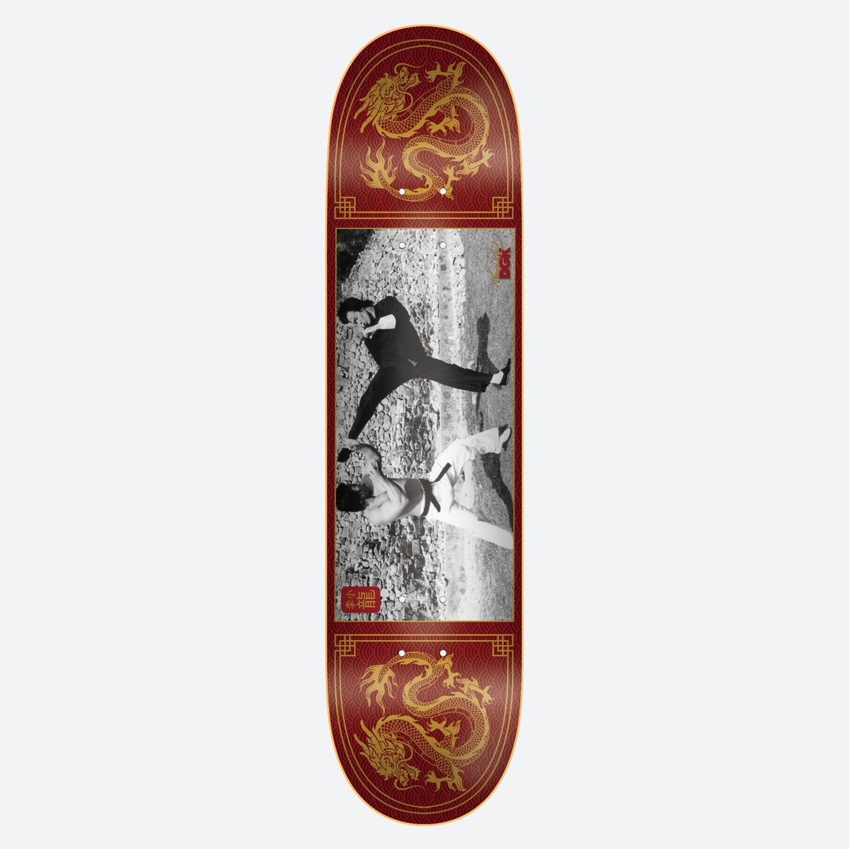 DGK x Bruce Lee Double Dragon skateboard deck: Black and white photograph of two martial artists mid-fight on a rocky ground, set in a red panel with gold Chinese dragons at the top and bottom and a gold border. Small red seal-style logos beside the photo.