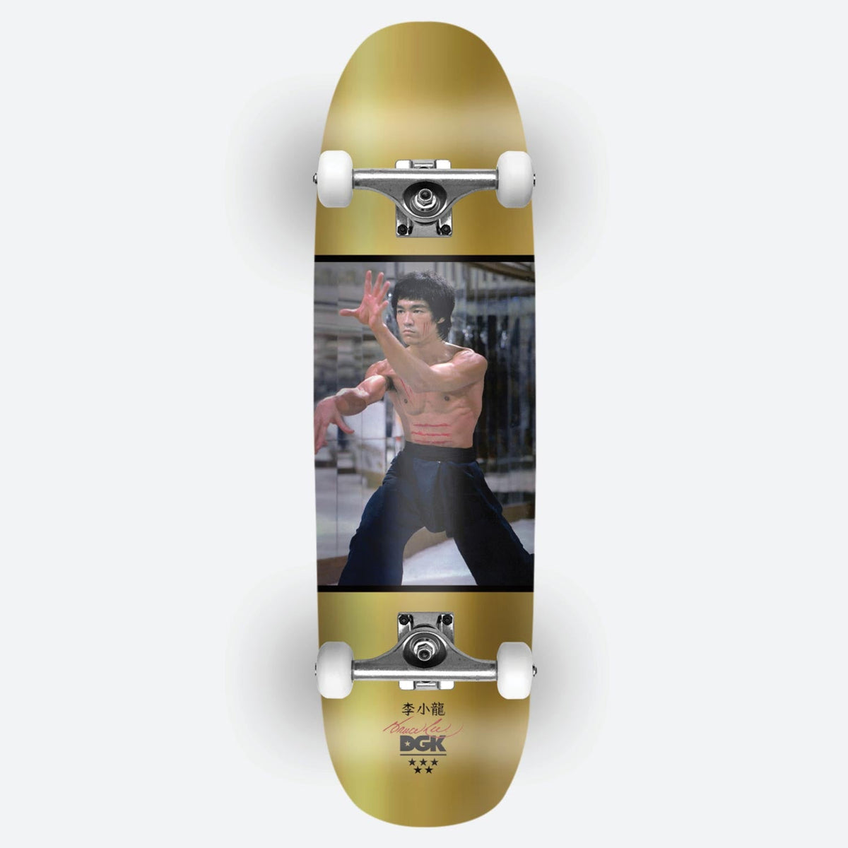 DGK x Bruce Lee Like Echo Foil Cruiser skateboard deck: Photograph of a shirtless martial artist in a fighting stance, set in a black-bordered panel across a gold foil cruiser deck, with Chinese characters, a signature and the DGK logo at the tail. Shown as a complete with trucks.