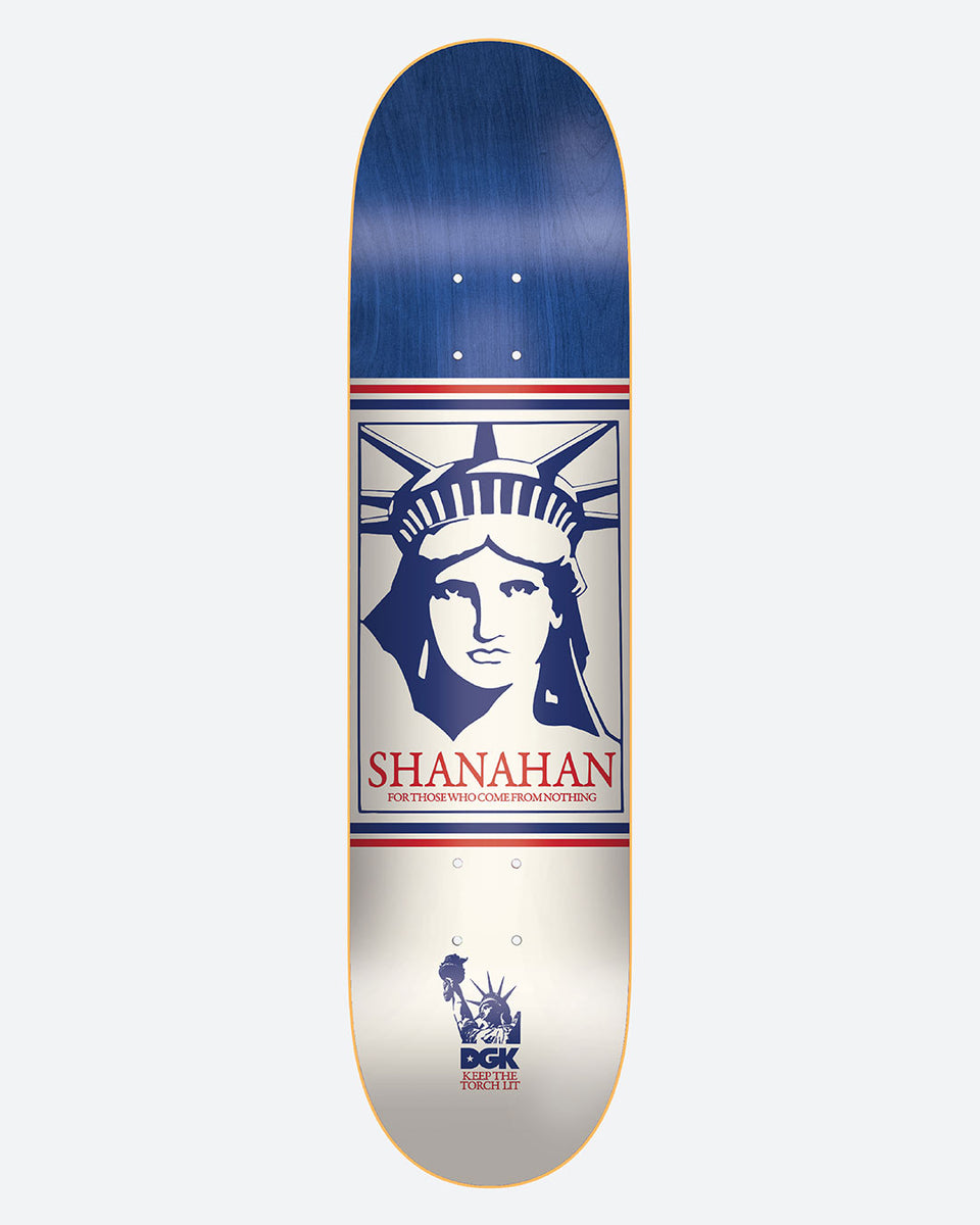 DGK Liberty Shanahan skateboard deck: A framed blue and white illustration of the Statue of Liberty's face on a cream centre with a navy top, red and navy lines, Shanahan lettering, and a small DGK torch logo at the tail.
