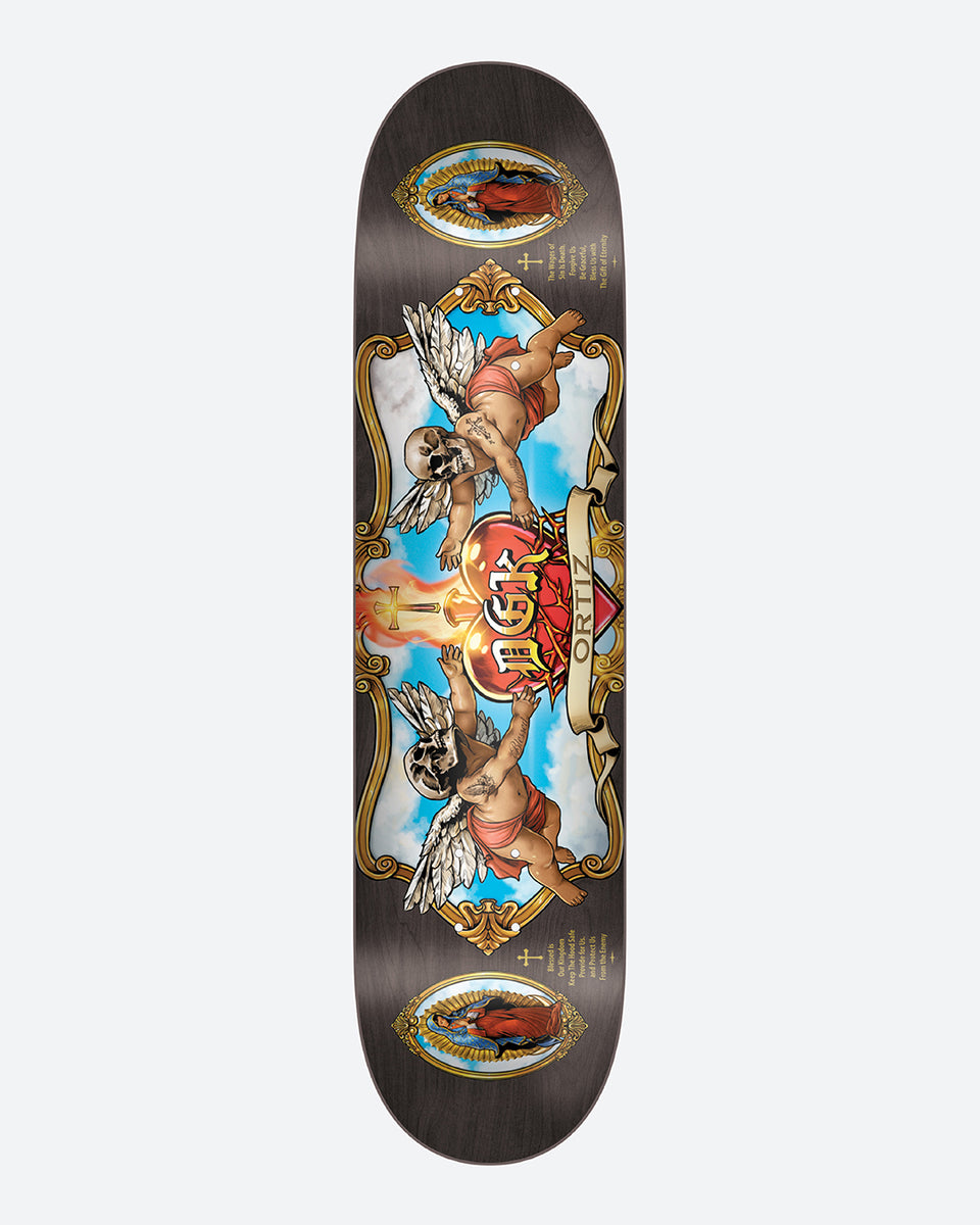 DGK Oracion Ortiz 8.06 skateboard deck: Ornate gold-framed panel showing two winged cherubs with skull heads, either side of a flaming sacred heart with a dagger and DGK banner, against blue sky. Small framed religious portraits at top and bottom on a black deck.