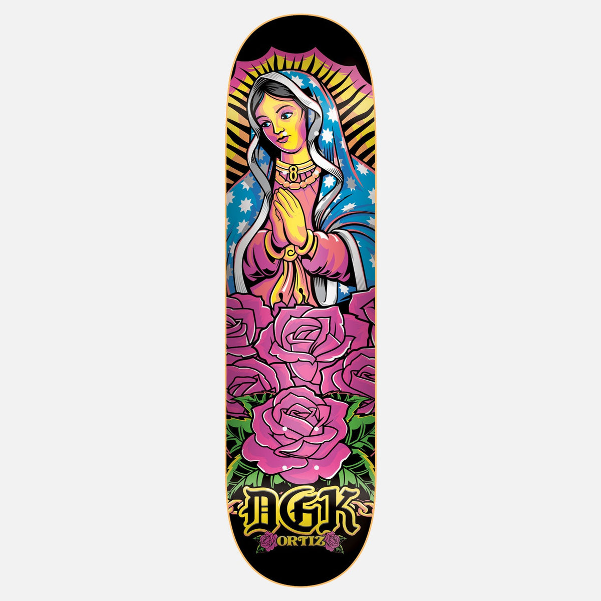 DGK Santa Del Barrio Ortiz 8.1 skateboard deck: Colourful tattoo-style Virgin of Guadalupe with praying hands, starry blue mantle and golden rays, above a bed of pink roses, on black. DGK in gold gothic lettering and ORTIZ at the bottom.