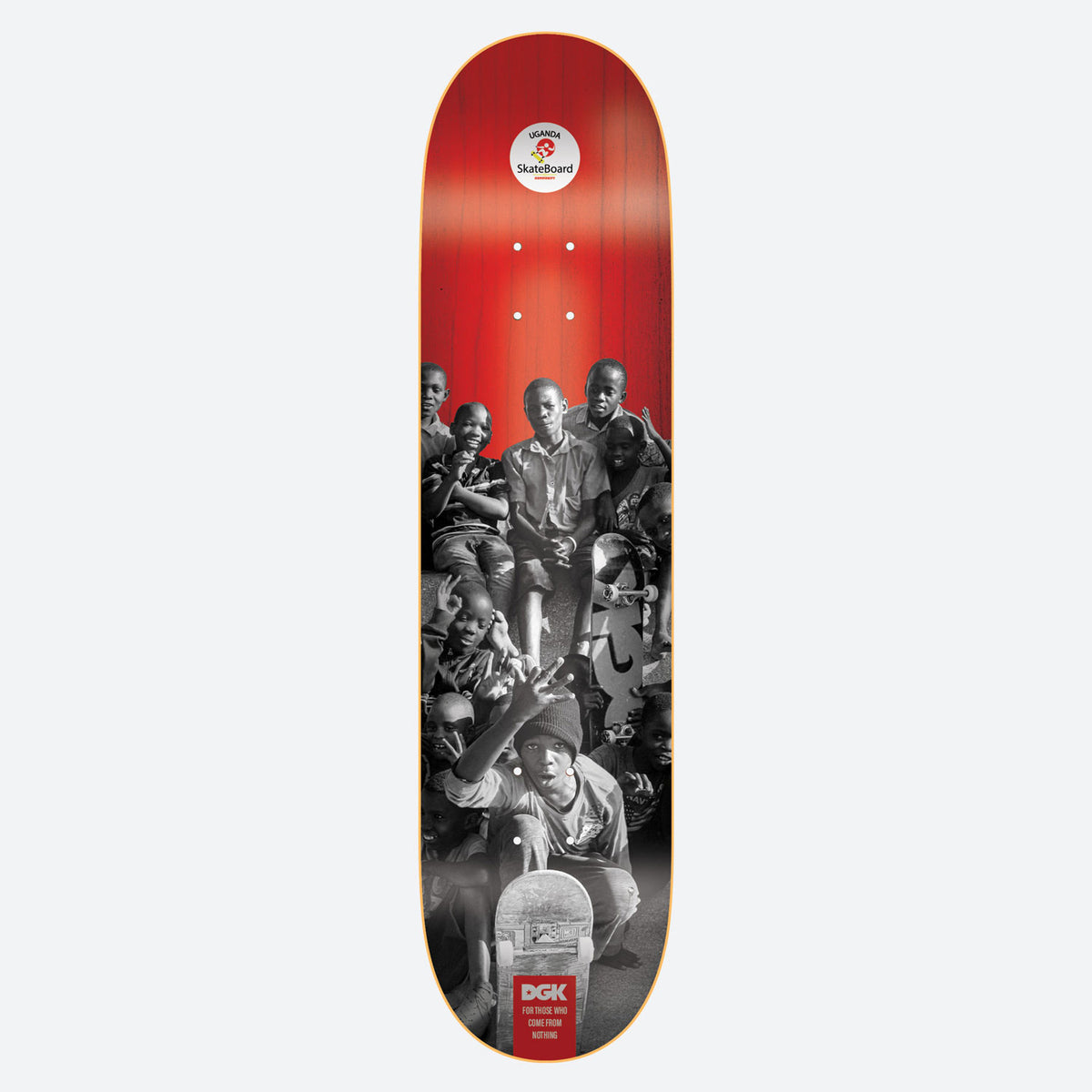 DGK Uganda Skate Community 8.25 skateboard deck: Black and white group photo of Ugandan children and teenagers posing with skateboards, fading into a red top with a Uganda Skateboard badge. DGK logo and a short slogan at the tail.