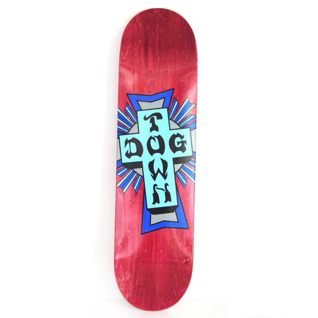 Dogtown Street Cross Logo - Assorted Colors / Assorted Cross skateboard deck: A turquoise cross with black gothic Dogtown lettering, backed by blue rays and a grey halo, on a red-stained deck.
