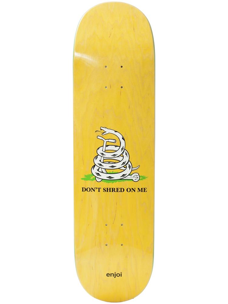 Enjoi dont shred board skateboard deck: Parody of the Gadsden flag: a white coiled snake on a patch of grass, its tail ending in a skateboard wheel, with 'DON'T SHRED ON ME' beneath. Enjoi wordmark at the tail on a yellow woodgrain.