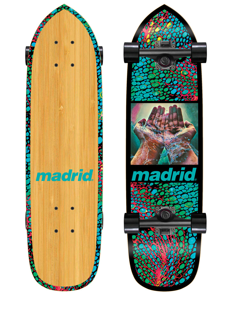 Madrid 76 27 skateboard deck: Cruiser-shaped board with a teal, red and green cellular pattern border, and a framed painting of cupped hands holding splashing water. Madrid logo in teal beneath, on black, with a bamboo underside.