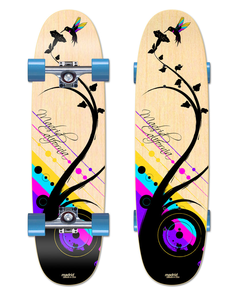 Madrid Combi 32.5 skateboard deck: Black silhouette of a curling plant with leaves and a colourful hummingbird at a flower, over diagonal stripes and circles in yellow, cyan, magenta and purple, on natural wood with script lettering. Shown top and side-by-side.