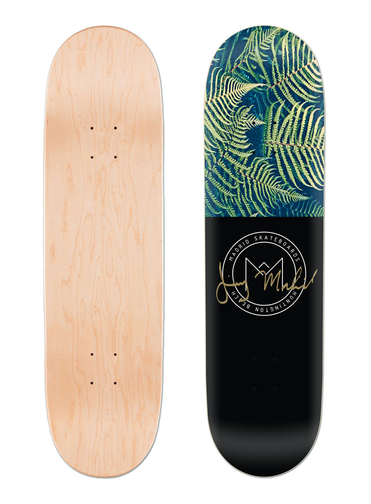Madrid Fern 8 skateboard deck: Deck split in two: fern fronds photographed in green on blue at the top, and plain black below with a circular Madrid Skateboards Huntington Beach logo and a gold signature. Plain natural maple bottom view alongside.