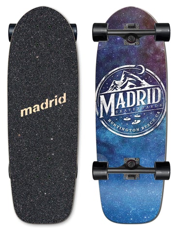 Madrid Marty 29.25 skateboard deck: Starry galaxy gradient from purple to blue with a circular white Madrid Skateboards Huntington Beach badge showing mountains, a crescent moon and flying saucers. Shown top and bottom on a small cruiser with black trucks.