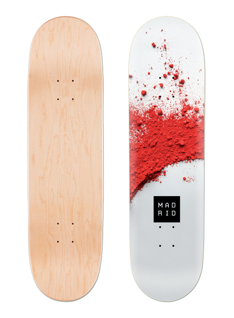 Madrid Pulver 8 skateboard deck: A close photograph of red powder pigment scattered across a pale grey-white surface, with a small black square Madrid logo near the bottom. The deck's bare maple underside is shown beside it.