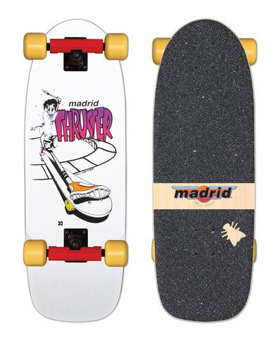Madrid Thruster OG Cruiser skateboard deck: A white cruiser with a manga-style cartoon skater riding a curved ramp, with a big orange-and-white shoe in the foreground and Madrid Thruster lettering in pink gradient. Shown with red trucks and yellow wheels, and the gritty top with a Madrid label.