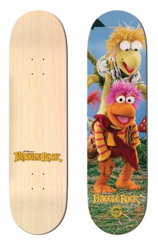 Madrid x Fraggle Rock Leapfrog 8 skateboard deck: A photograph of Fraggle Rock puppets, Gobo in an orange fur with a red scarf and pink hair and Wembley in yellow above him, in a meadow with a toadstool. The Fraggle Rock logo is at the foot; the plain wooden underside is also shown.