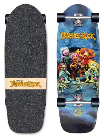 Madrid x Fraggle Rock Rock On Marty 29.25 skateboard deck: A photo of the Fraggle Rock puppet characters gathered at a cave mouth, one playing a guitar, with the orange Fraggle Rock logo above. Shown as a complete cruiser with the logo on a wood strip on the griptape.
