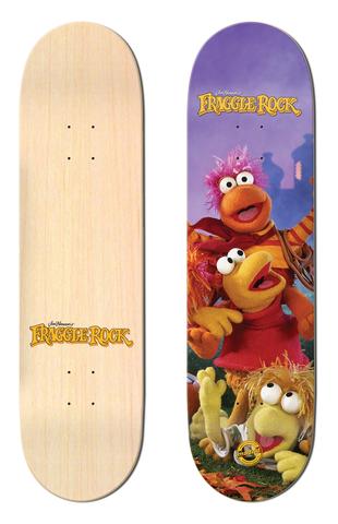 Madrid x Fraggle Rock Trio 8 skateboard deck: Photo-style scene of three Fraggle Rock puppets, pink-haired Gobo, Red and Wembley among autumn leaves, against a purple sky. The Fraggle Rock logo sits at the top, with a plain natural wood underside shown beside it.