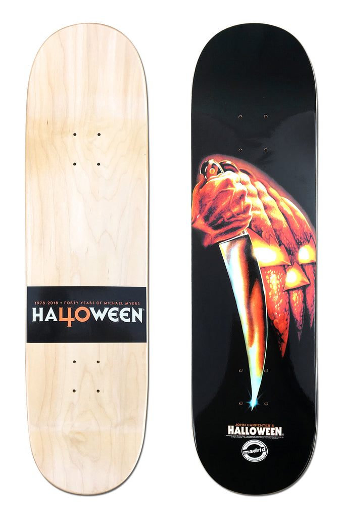 Madrid X Halloween - Slasher 8 skateboard deck: Movie poster artwork of a hand holding a kitchen knife in front of a glowing jack-o'-lantern, on black. The underside is natural wood with a black band for the Halloween 40th anniversary title.