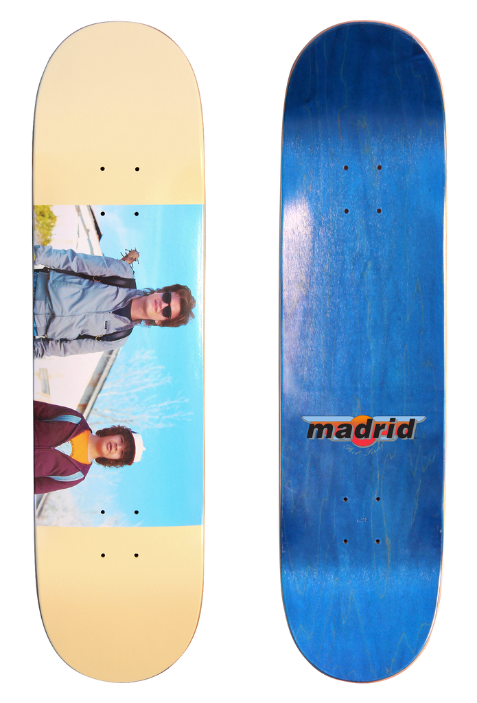 Madrid X Stranger Things - Steve & Dustin 8 skateboard deck: Cream deck with a colour photograph band across the middle showing two characters against a blue sky: a young man in sunglasses and a light jacket, and a boy in a cap and maroon jacket. The underside is blue with a Madrid logo.