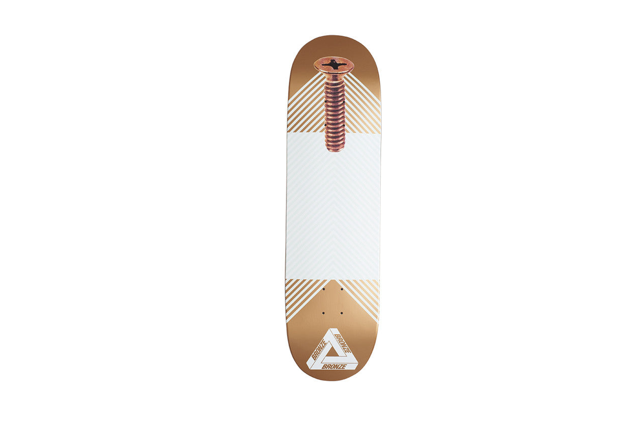 Palace Bronze Regal Board skateboard deck: Large bronze-coloured screw running down a white centre panel with fine chevron lines, on a bronze-tinted deck with the white Palace triangle logo near the tail.