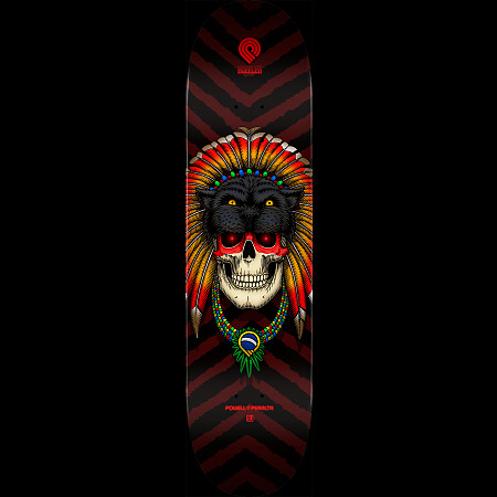 Powell Peralta Pro Kelvin Hoefler Skull - Shape 247 skateboard deck: Colour illustration of a human skull with red eyes wearing a black panther headdress and a feathered war bonnet in red, orange and yellow, with a beaded necklace bearing a Brazilian flag pendant, on a black and maroon chevron background.