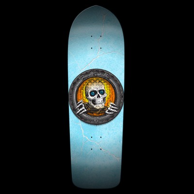 Powell Peralta Pool Light Ripper Large - Orange skateboard deck: Old-school shaped deck with a round metal-rimmed medallion at centre showing a skull with blue eyes and skeletal hands against an orange and yellow brick pattern. Light blue ground with white crack or lightning lines.