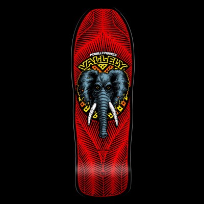 Powell Peralta Vallely Elephant - Red skateboard deck: A grey elephant head with white tusks and yellow eyes inside a yellow and orange tribal-style ring, under 'Vallely' lettering, on a red deck patterned with fine black feather-like lines.
