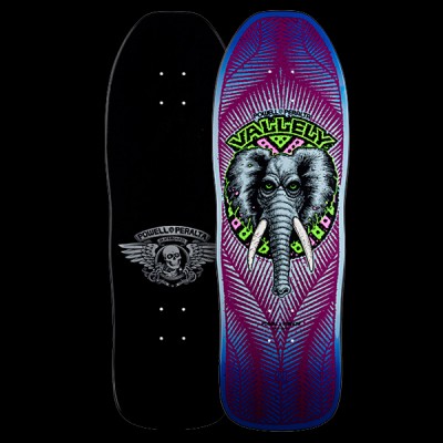 Powell Peralta Vallely Elephant - Purple skateboard deck: Grey elephant head with tusks and green eyes inside a circular green and pink badge, with Vallely lettering above, on a purple deck with blue edges and radiating feather-like lines. Underside shows a winged skull logo. Both sides shown.