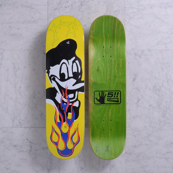 Quasi Bigbiz Yellow skateboard deck: Both sides shown. A black-and-white cartoon duck-like character in a cap, grinning with blue and orange flames below its beak, on a yellow deck with faint green scribbles. The underside is green with a black hand logo.