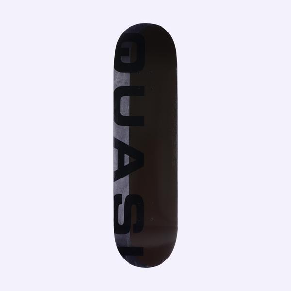 Quasi Mono Phade Black skateboard deck: Large black capital letters spelling Quasi run vertically down the left side, over a split background of grey fading panel and a dark brown-black field.