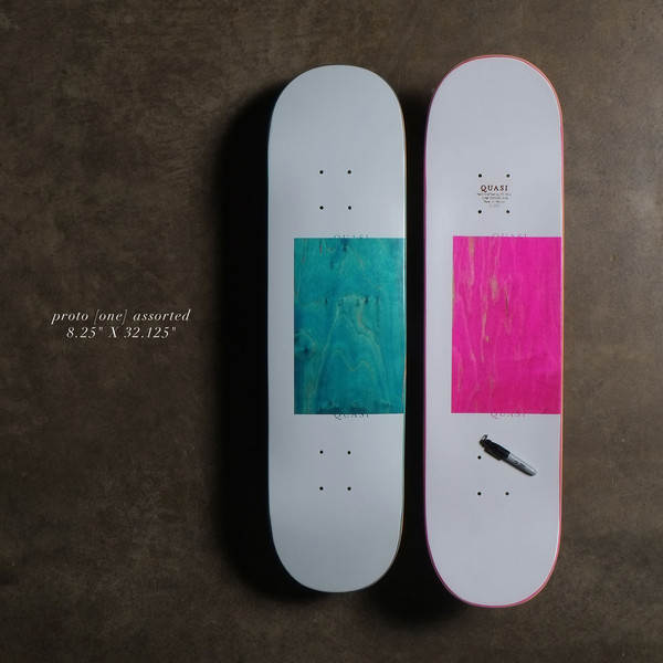 Quasi Proto - Assorted skateboard deck: Plain pale grey deck with a large square of exposed dyed wood veneer, shown in teal on one and hot pink on the other, with small Quasi lettering above and below the square. Two decks shown.